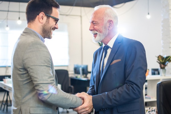 Senior Executive Shaking Hands With Young Employee At Office
